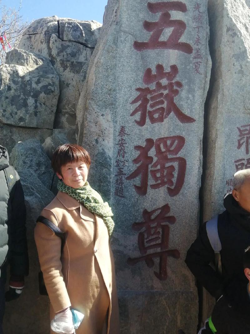 男子攀爬五岳独尊石,游客爬上五岳独尊石刻拍照